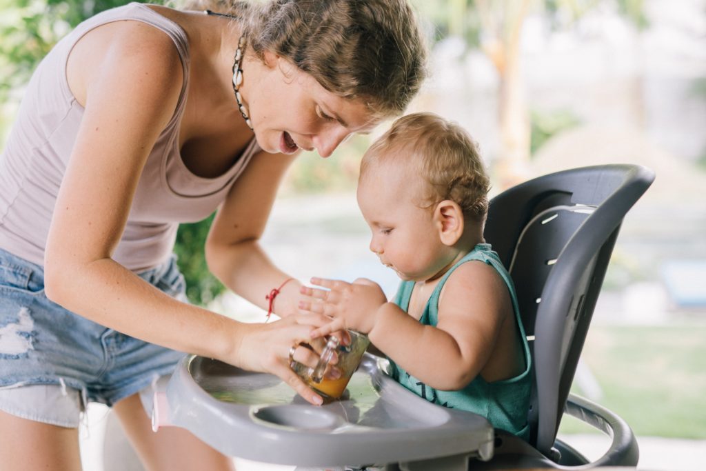 a mom feeding a baby in a high chair